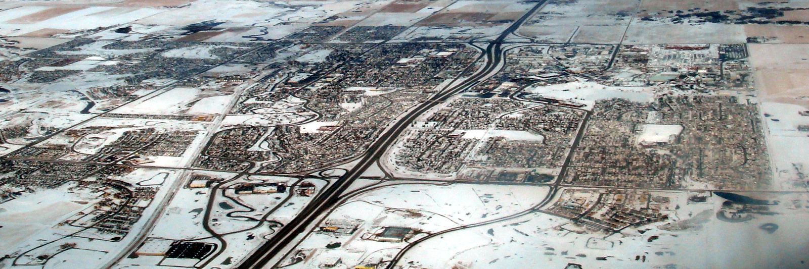 Winter aerial view of Airdrie, Alberta, with snow-covered streets and the Nose Creek valley